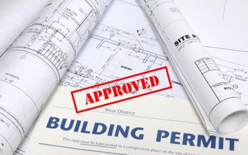 Approved building permit paperwork on top of rolled construction plans